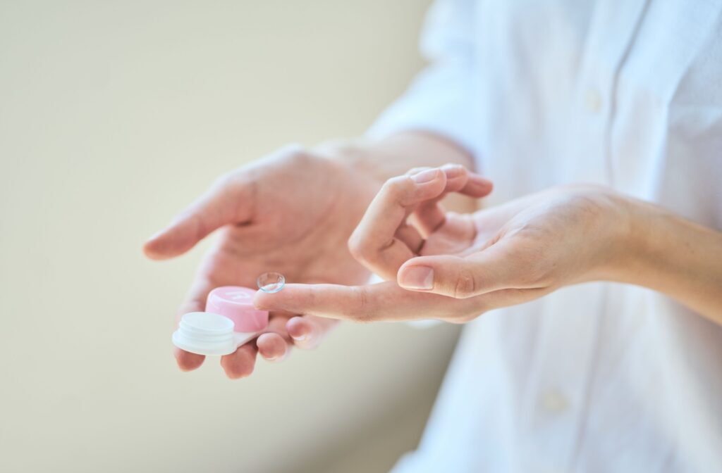 A pair of hands holding contact lenses.