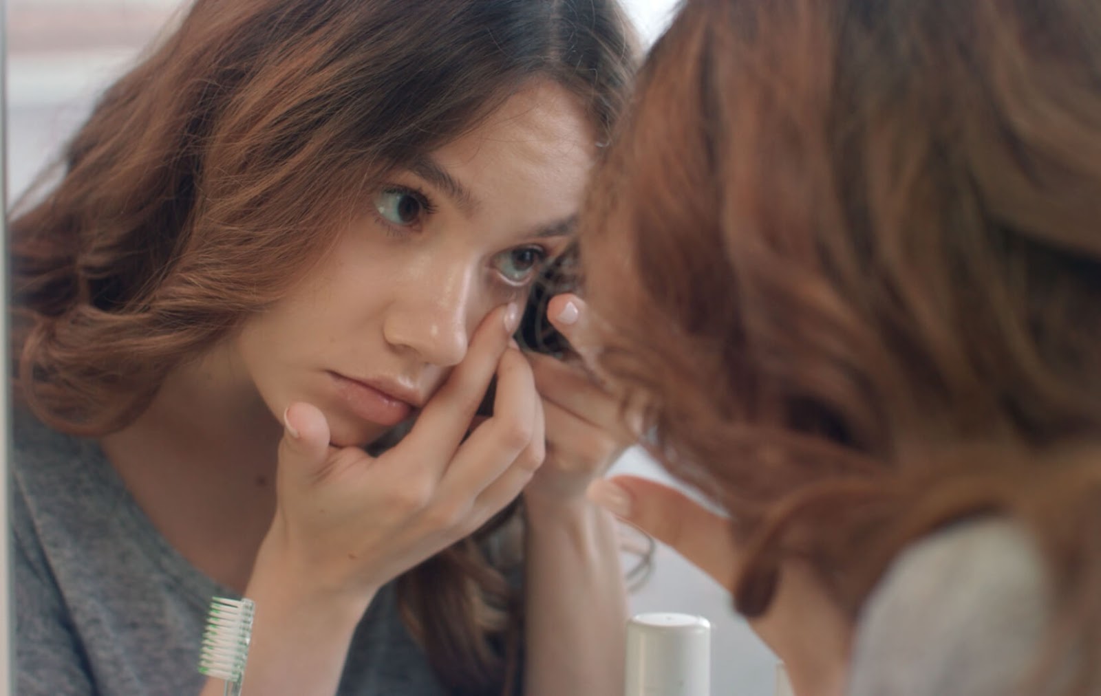 A young person gently removes an inside-out contact lens from their eye.